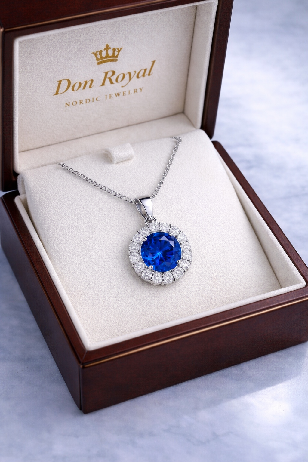 Blue sapphire diamond halo pendant featuring natural royal blue sapphire surrounded by brilliant diamonds set in white gold in box